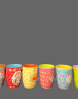 Set of colorful patterned mugs on a wooden surface with a chalkboard background