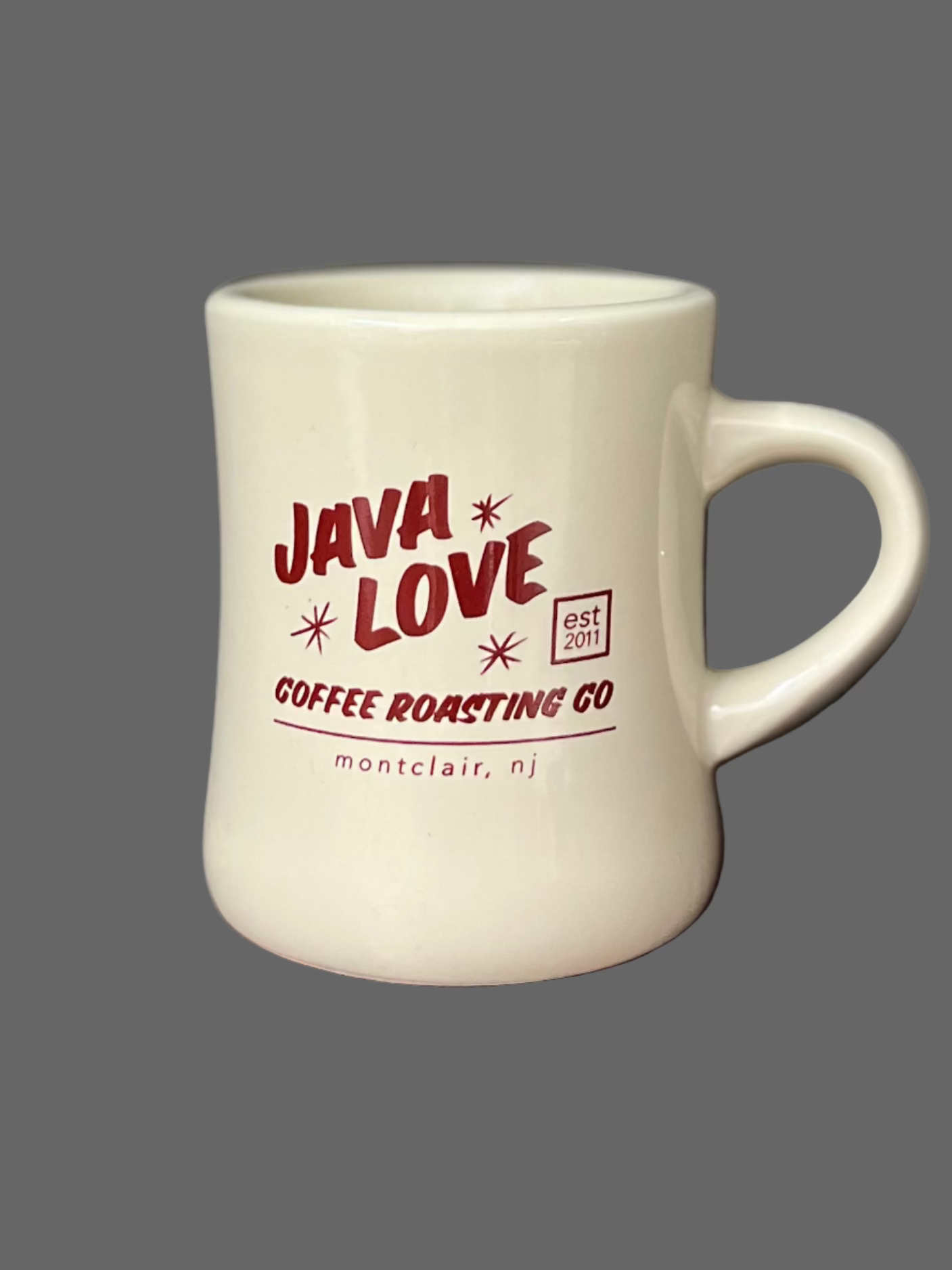 White mug with red and black text on a wooden surface and dark background