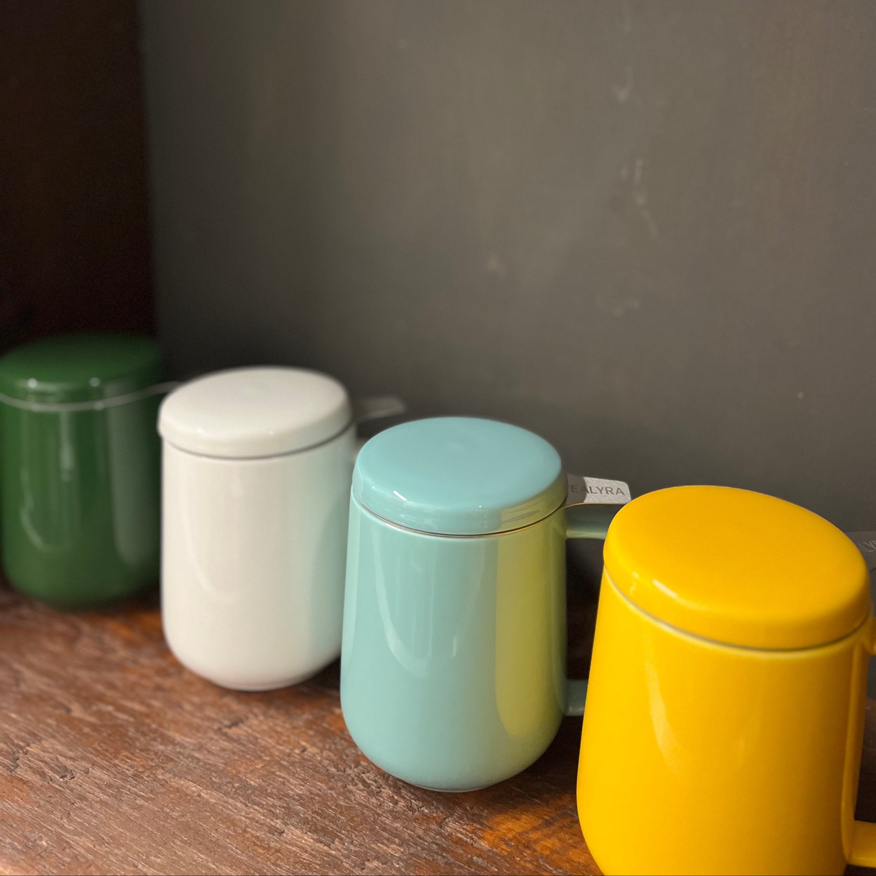 Four colorful ceramic jars with lids on a wooden surface against a dark background