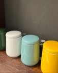 Four colorful ceramic jars with lids on a wooden surface against a dark background